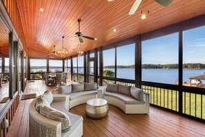 A spacious deck with a curved sofa, a round coffee table, and a ceiling fan. - Stunning Big Water Views - Pet-friendly, Game Room (Sparta)