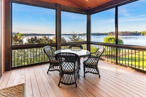 A covered deck with a glass table and chairs, overlooking a lake. - Stunning Big Water Views - Pet-friendly, Game Room (Sparta)