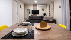 A dining area with a wooden table, plates, glasses, and cutlery. - Casa Maré | 250m from Mariscal beach (Bombinhas)