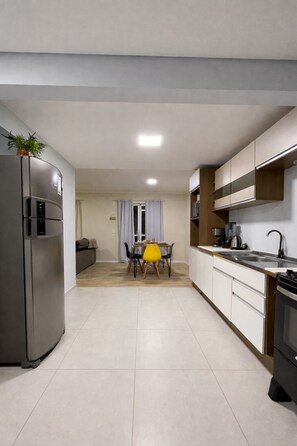 Eine moderne Küche mit Kühlschrank, Herd und Essbereich mit Tisch und Stühlen.