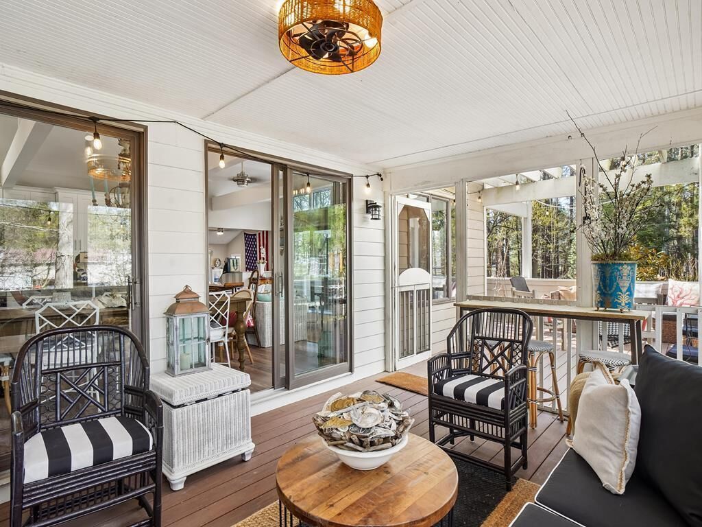 An outdoor patio area with wicker furniture, a wooden table, and a bowl of oysters.