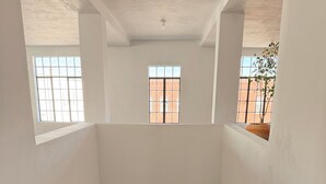 Un intérieur à plusieurs niveaux, doté d’un escalier central, de murs blancs et de grandes fenêtres.