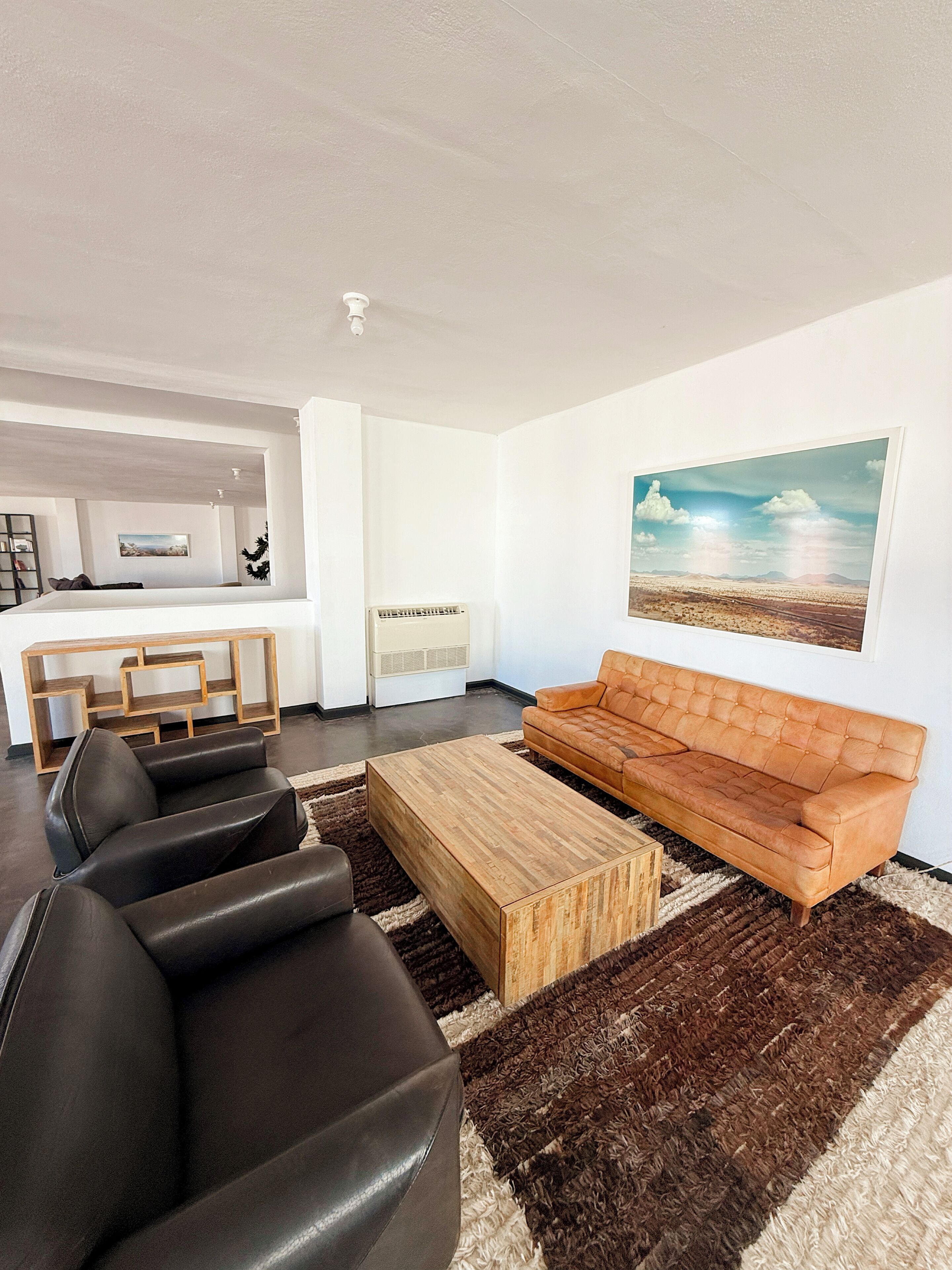 Un salon moderne avec un canapé, une table basse et un tableau accroché au mur.