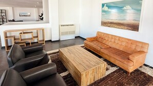 Un salon moderne avec un canapé, une table basse et un tableau accroché au mur.