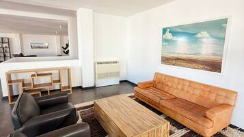 Un salon moderne avec un canapé, une table basse et un tableau accroché au mur.