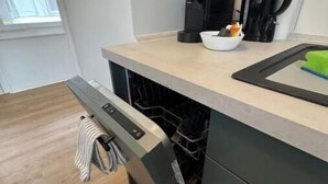 A kitchen with a dishwasher, a coffee maker, and a bowl on the counter. - Vacation village Seddiner See - Bungalow 6 (Seddiner See)