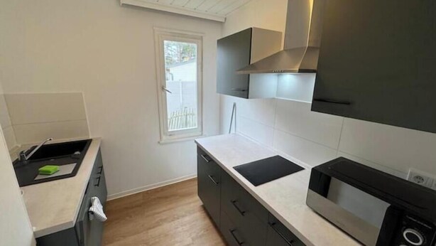 A compact kitchen with a microwave, stove, and a window. - Vacation village Seddiner See - Bungalow 6 (Seddiner See)