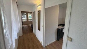 A hallway with wooden flooring, white walls, and a door leading to a bathroom. - Vacation village Seddiner See - Bungalow 6 (Seddiner See)
