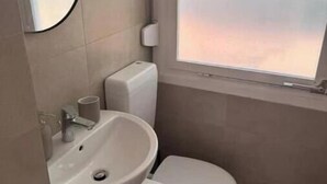 Un bagno piccolo con il water, un lavandino e una finestra.