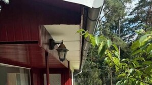 Un edificio rosso con una porta in vetro, un portico con sedie e un'area giardino.