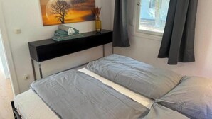 Una camera da letto con un letto, un comodino, un quadro, una finestra con tende e vista sull'esterno.