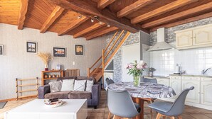 A modern kitchen with white cabinets, a wooden ceiling, and a dining area with a table and chairs.