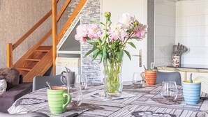 A dining table with a vase of flowers, a coffee mug, and a knife.