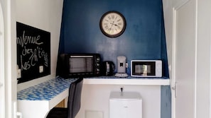 Eine Küchenzeile mit einer Tafel, zwei Mikrowellen, einer Kaffeemaschine und einer Uhr an der Wand.
