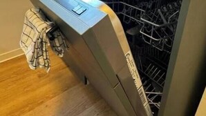 Une cuisine compacte dotée d’un lave-vaisselle intégré, d’une fenêtre donnant sur un espace verdoyant et d’une serviette accrochée à la porte.