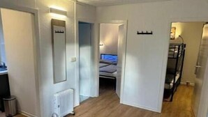 Un couloir avec un radiateur, un lit en arrière-plan et un lit superposé sur la droite.