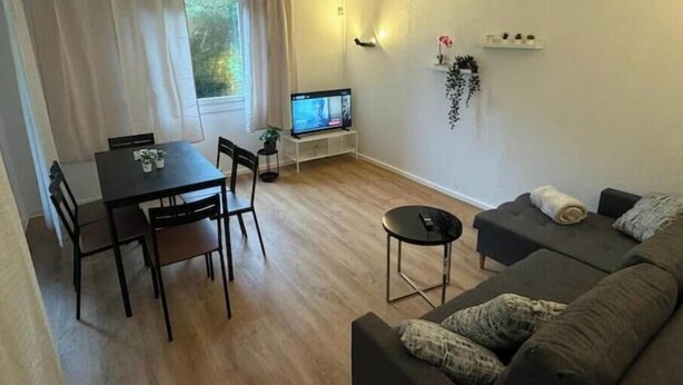 Un salon comprenant un canapé, une table à manger avec des chaises, un téléviseur et une petite table d’appoint.