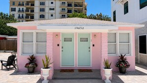 A pink building with two doors, numbered 19652, and potted plants in front. - Sunset Cottages Suite 1 (Indian Shores)