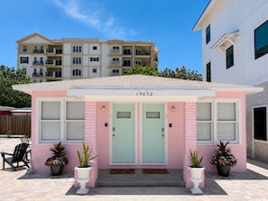 Un edificio rosa con dos puertas, numeradas 19652, y plantas en macetas al frente.