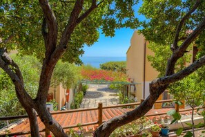 A courtyard with a view of the sea, surrounded by trees and potted plants. - Casa Ilune (Cala Gonone)