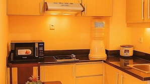 Cocina compacta con armarios de madera, microondas, cafetera y tostadora.