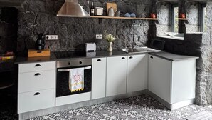 Een landelijke keuken met stenen muren, houten balken in het plafond en vloertegels met een patroon.