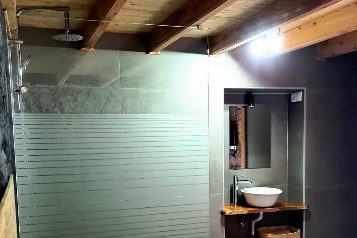 A bedroom with a bed, a bedside table, a mirror, and a built-in sink.