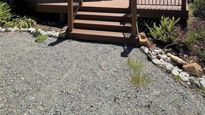 Ein Haus mit einer Terrasse, einer Veranda und einer Auffahrt mit Kies.