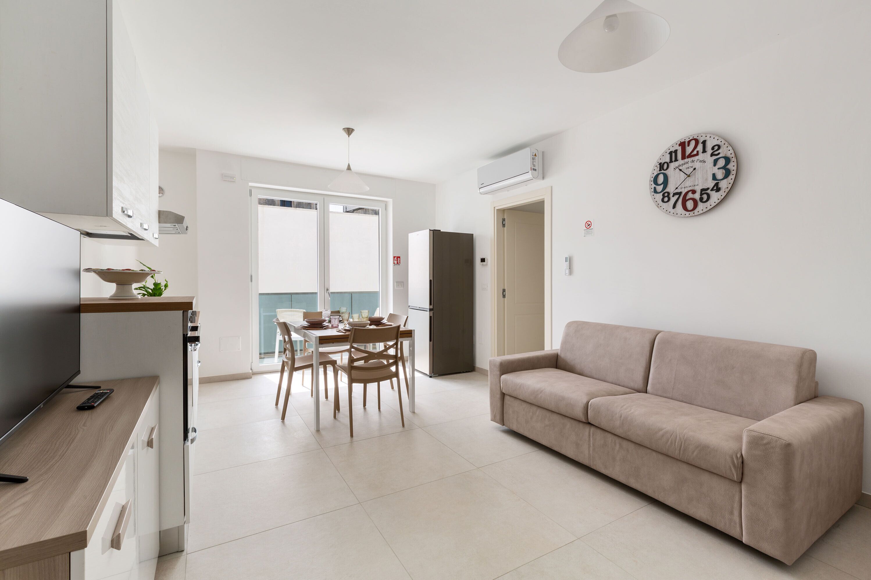 A modern living space with a kitchen, dining area, and a sofa.