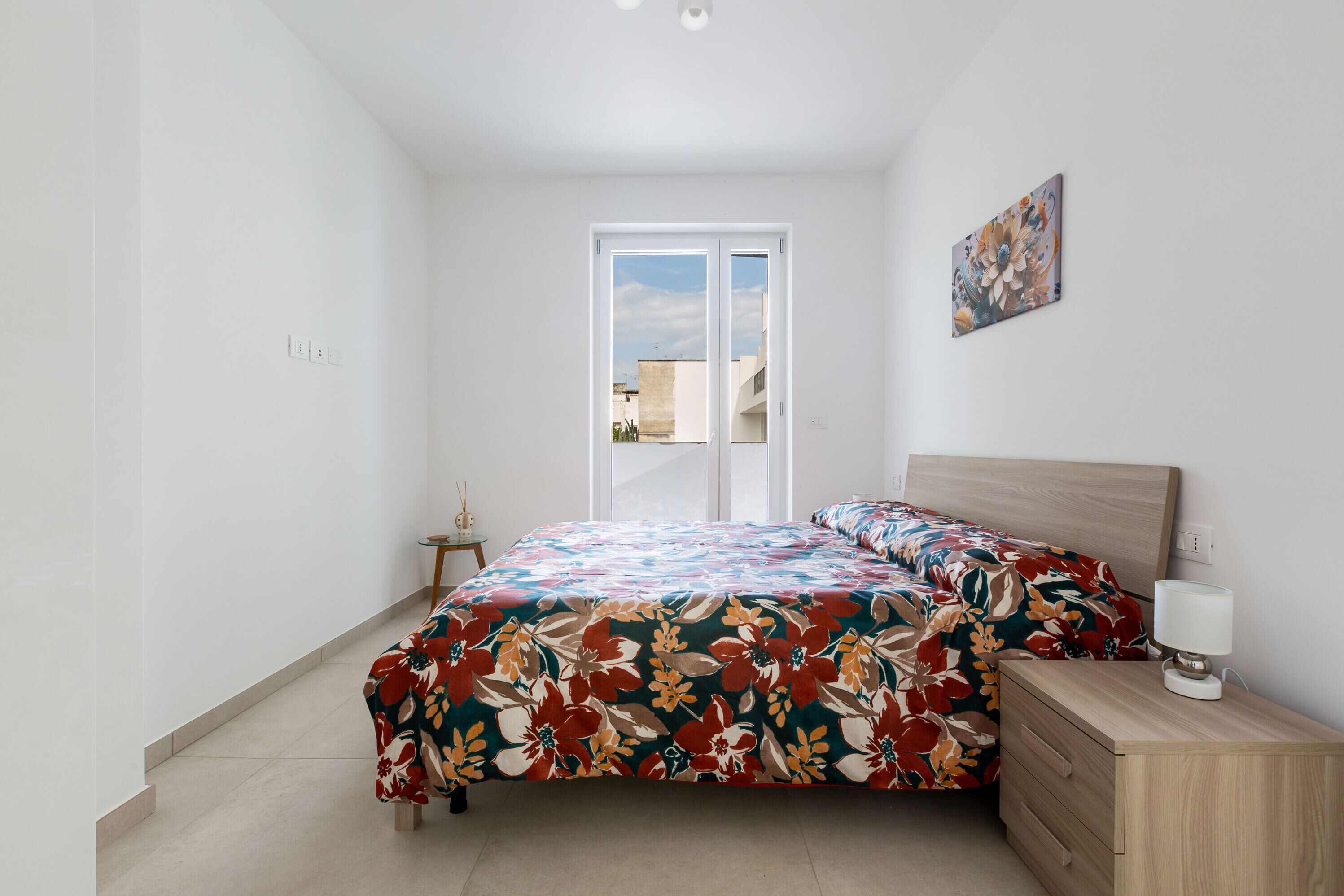 Une chambre à coucher avec un lit, une table de chevet, une lampe et un tableau au mur.