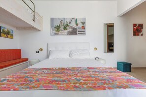 Un dormitorio con una cama, un banco rojo, un cuadro, un espejo y una planta en maceta.