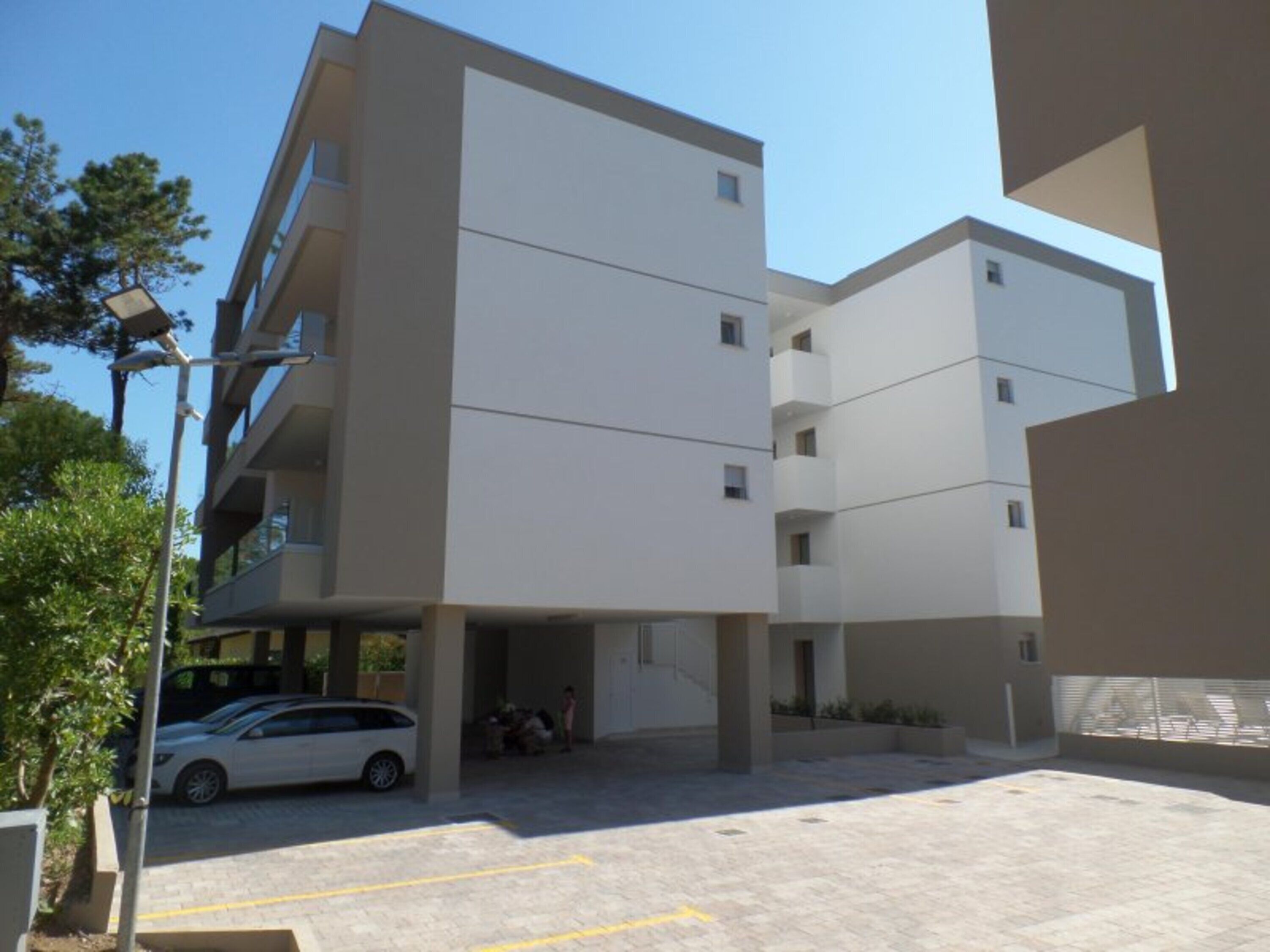 Un edificio de varios pisos con un estacionamiento al frente.