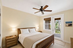 Ein Schlafzimmer mit Bett, Nachttischlampen, Deckenventilator, Fenster mit Aussicht und einer Tür.