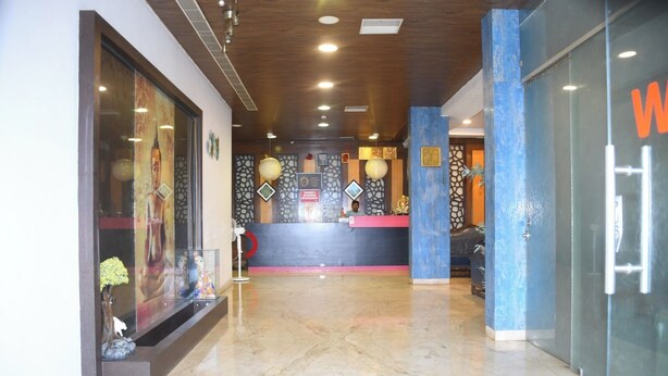 A reception area with a marble floor, a reception desk, and a wall with decorative elements.