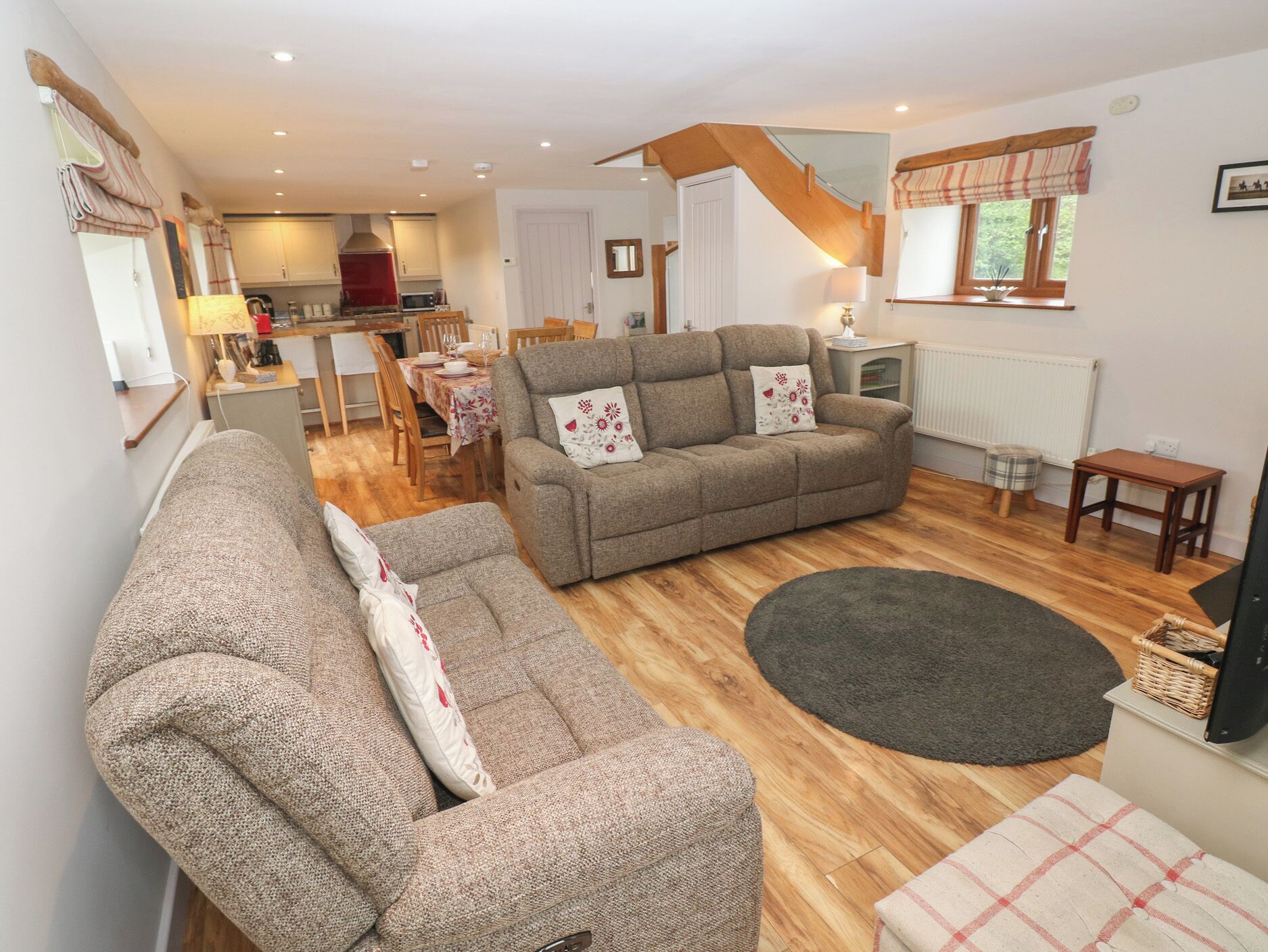 A cozy living room with a sofa, a dining table, and a kitchen in the background.