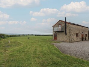A stone building with a balcony, a gravel driveway, and a grassy field. - The Gallops (Barry)