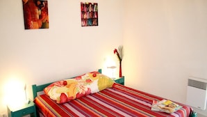 Un lit avec une couvre-lit à rayures, une lampe de chevet et un cadre photo sur une table de chevet.