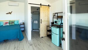 Quarto com cama, cozinha compacta, porta corrediça estilo celeiro e teto com iluminação embutida.