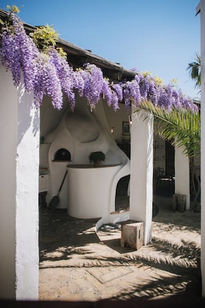 Ein weißes Gebäude mit einer gebogenen Struktur, einem kleinen Tisch und einem Blumentopf.