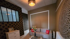 Un salon moderne avec un canapé, une table basse en verre, un meuble blanc et un radiateur.