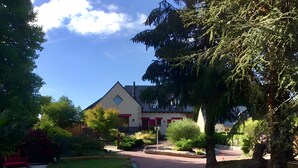 Une rue résidentielle bordée de maisons, d’arbres et d’une allée sinueuse menant à une propriété.