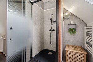 A modern bathroom with a glass shower enclosure, a white towel rack, and a small wooden stool. - Between Saint-Malo, Dinan, Mont-Saint-Michel: Bed & Breakfast - 3 Bedrooms (Miniac-Morvan)