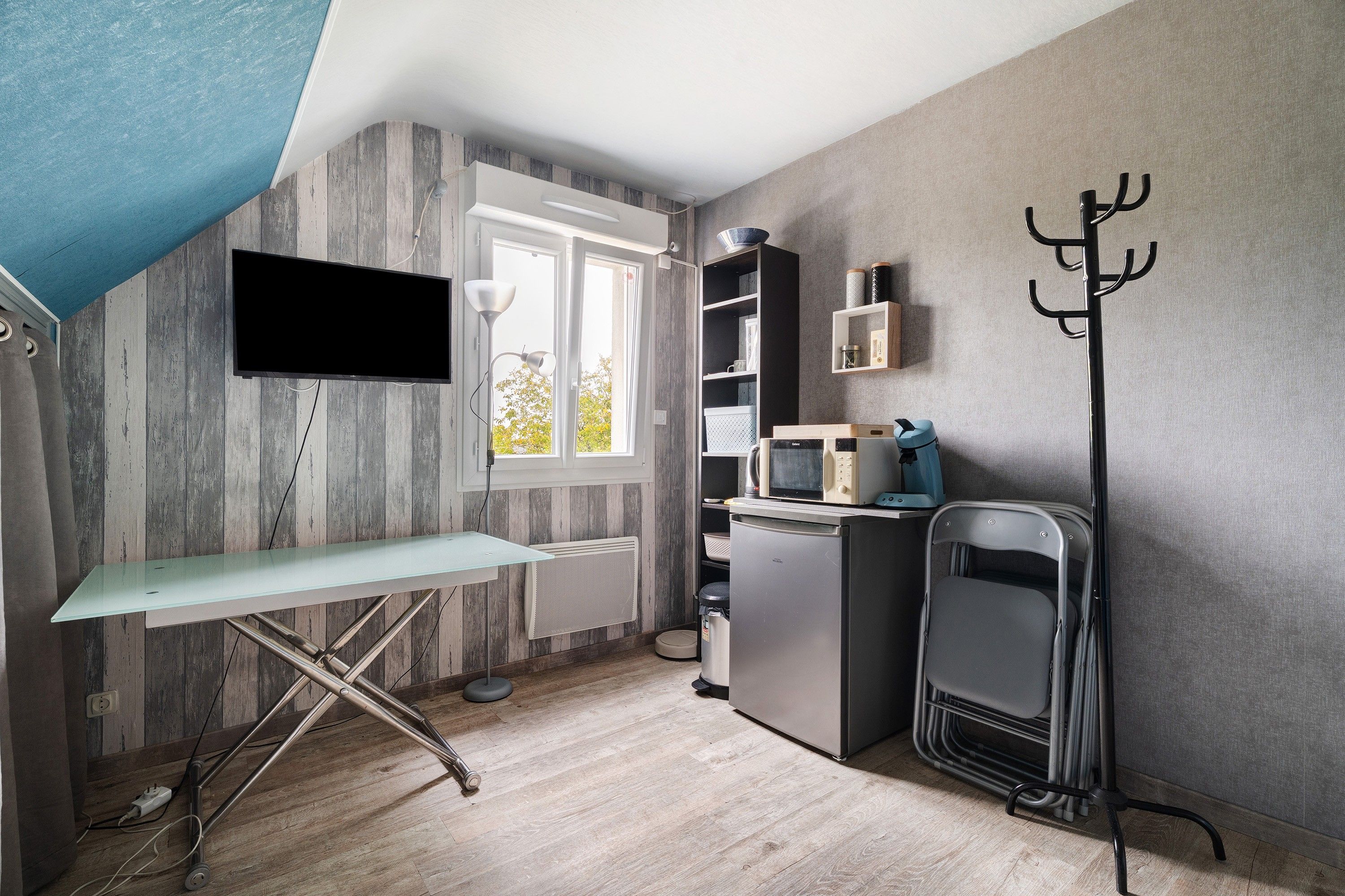 A compact kitchen with a flat-screen TV, a microwave, and a compact refrigerator.