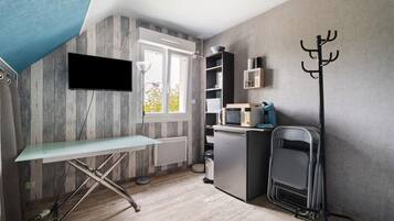 A compact kitchen with a flat-screen TV, a microwave, and a compact refrigerator.
