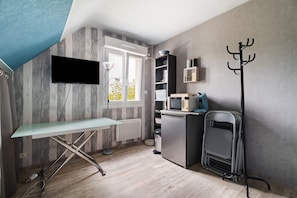Eine kleine Küche mit Flachbildfernseher, Mikrowelle und Mini-Kühlschrank.