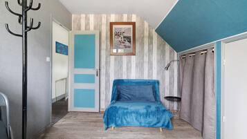 A bedroom with a bed, a coat rack, a door, and a wall with a picture.