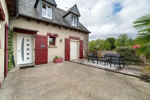 A two-story house with a gravel driveway, a red door, and a patio with outdoor furniture. - Between Saint-Malo, Dinan, Mont-Saint-Michel: Bed & Breakfast - 3 Bedrooms (Miniac-Morvan)