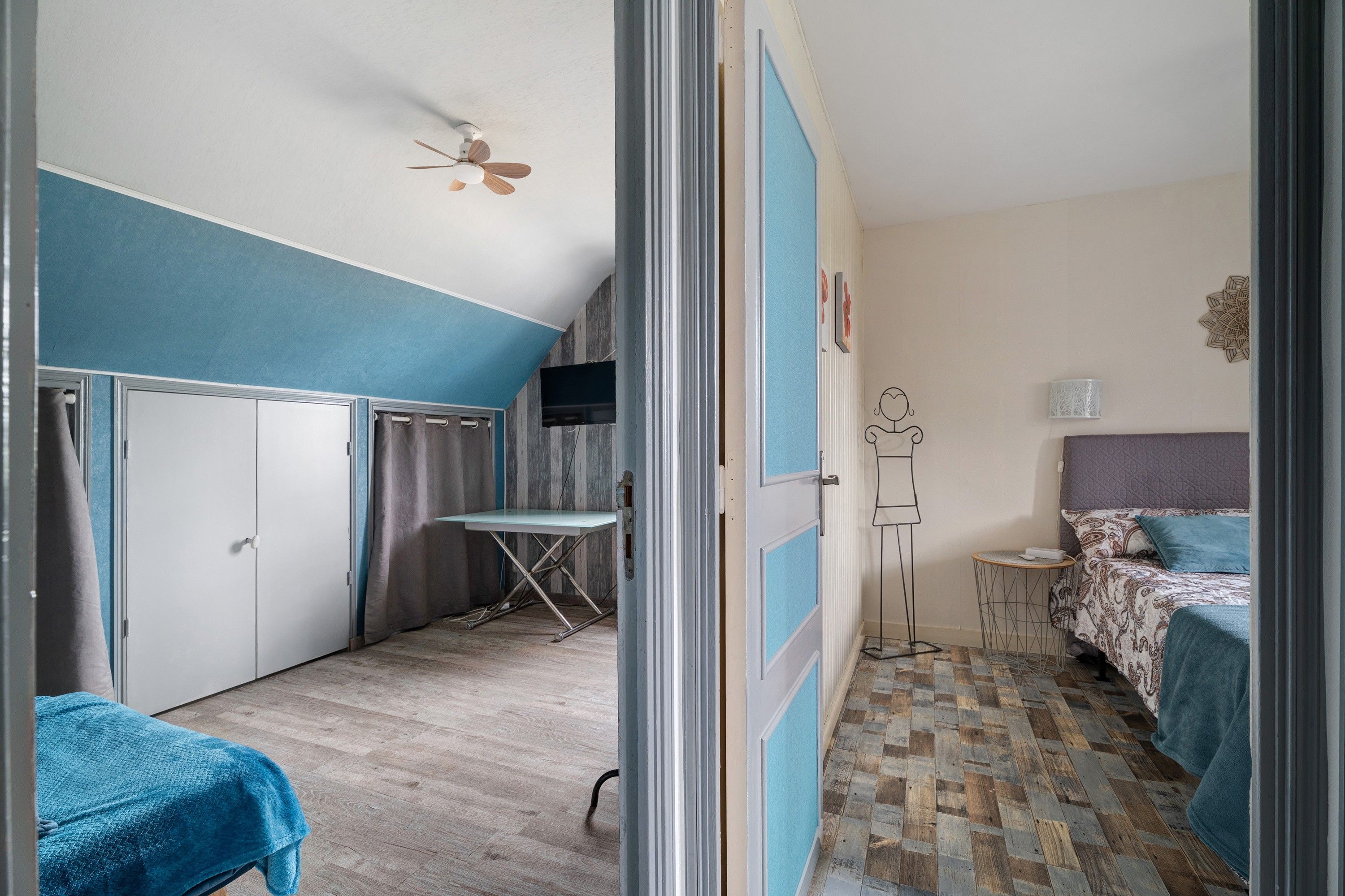 Une pièce comprenant un lit, un bureau, une chaise, une armoire et un ventilateur de plafond.