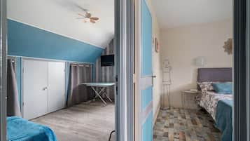 Une pièce comprenant un lit, un bureau, une chaise, une armoire et un ventilateur de plafond.