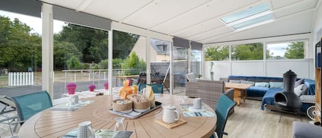 A modern outdoor dining area with a round table, chairs, and a variety of tableware.